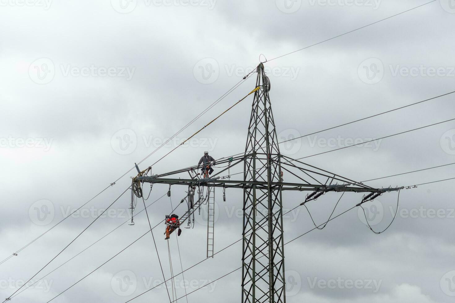 power lines of grey sky with working men photo