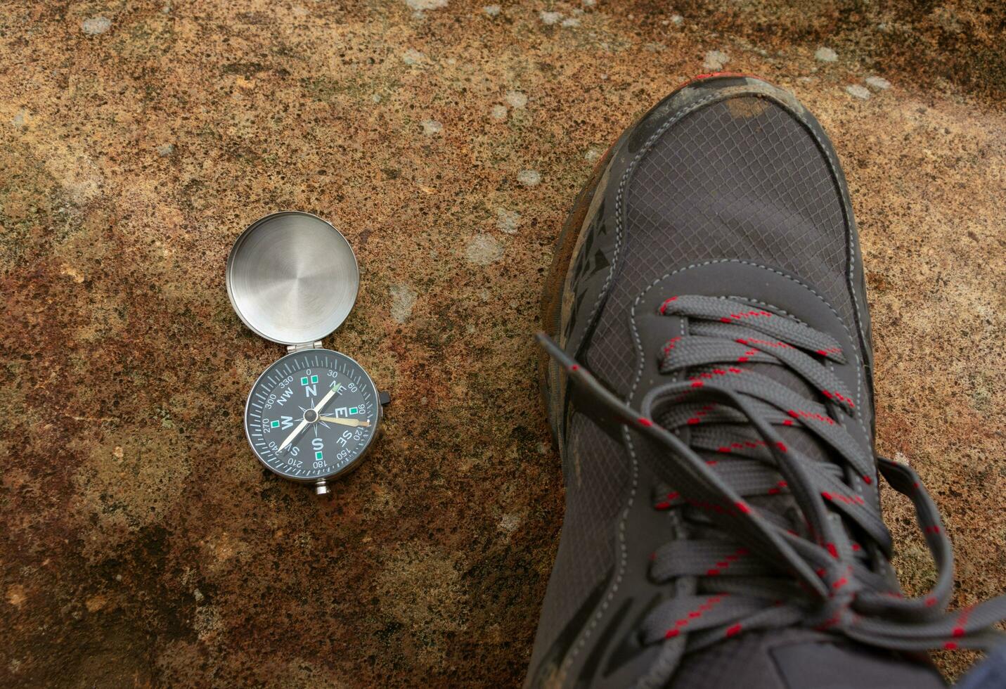 Concept for traveling and adventure. A compass and a shoe placed on a giant rock, after some edits. photo