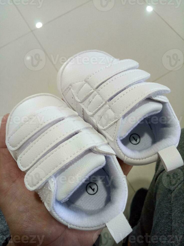 Photo of a cute little white baby shoe with triple adhesive