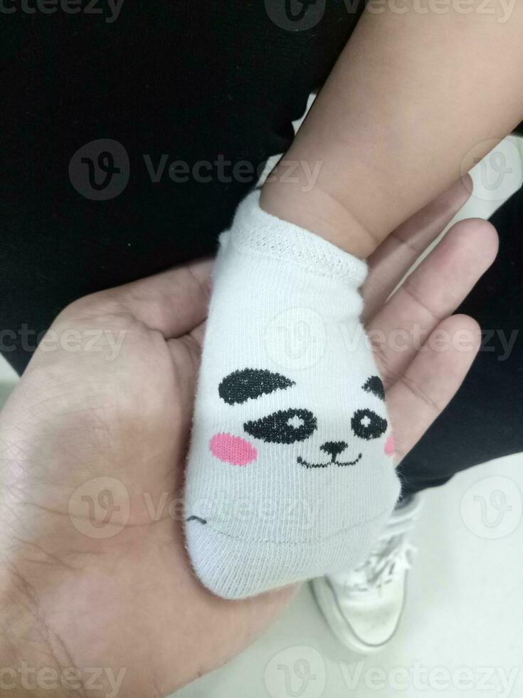 Photo of a baby's foot in a sock with a cute panda face on it