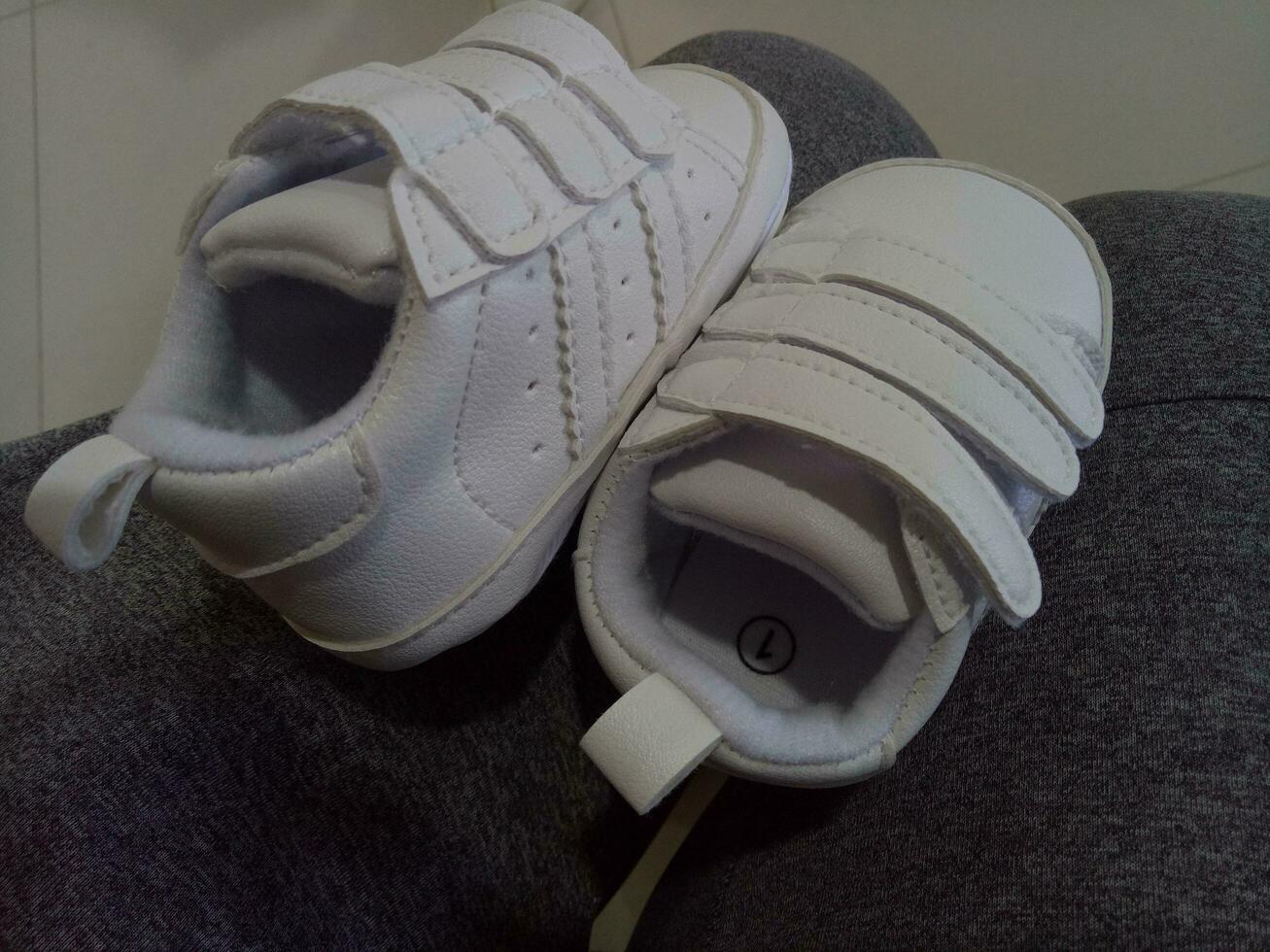 Photo of a cute little white baby shoe with triple adhesive