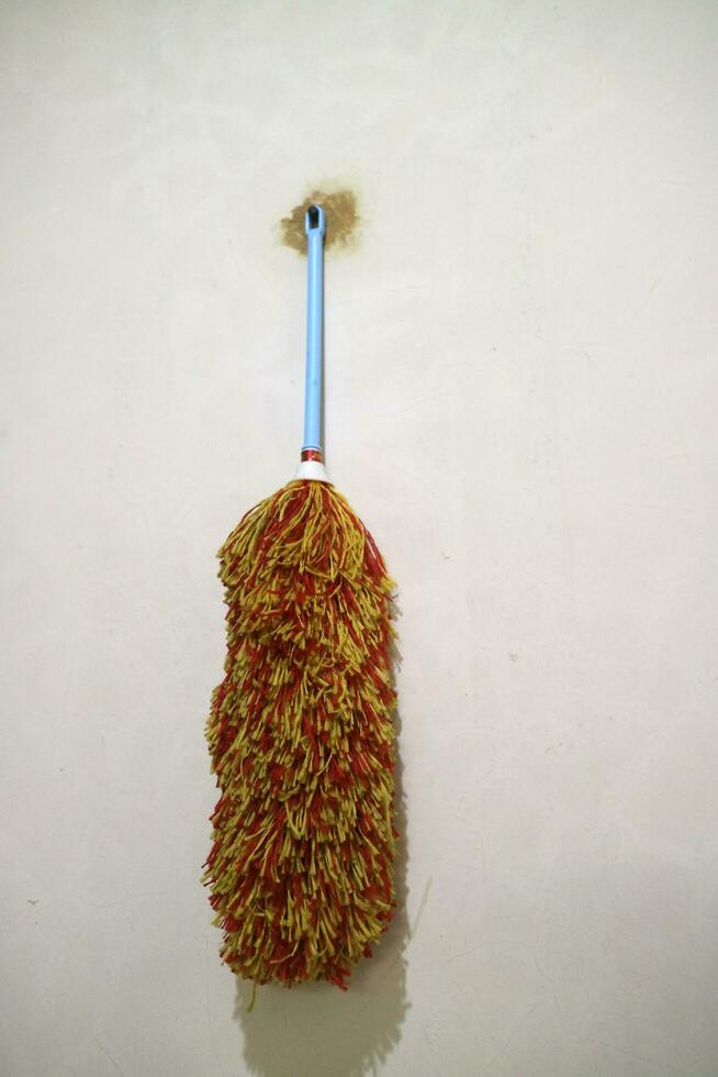 A duster with red yellow feathers, hangs on the wall photo