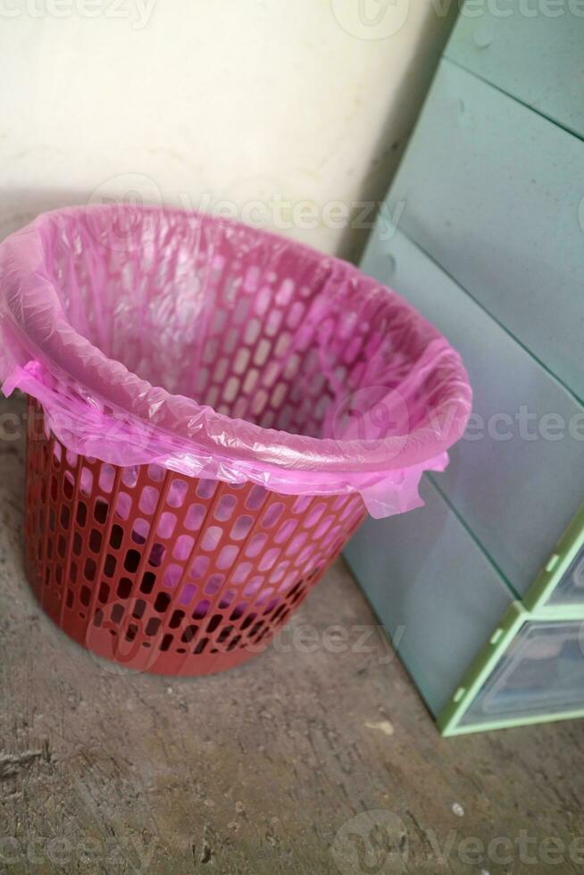 Red trash can covered with pink plastic photo