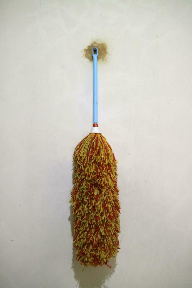 A duster with red yellow feathers, hangs on the wall photo
