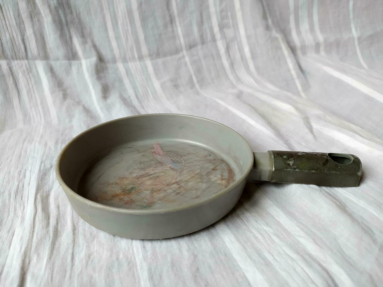 The gray frying pan is photographed on a white cloth background photo