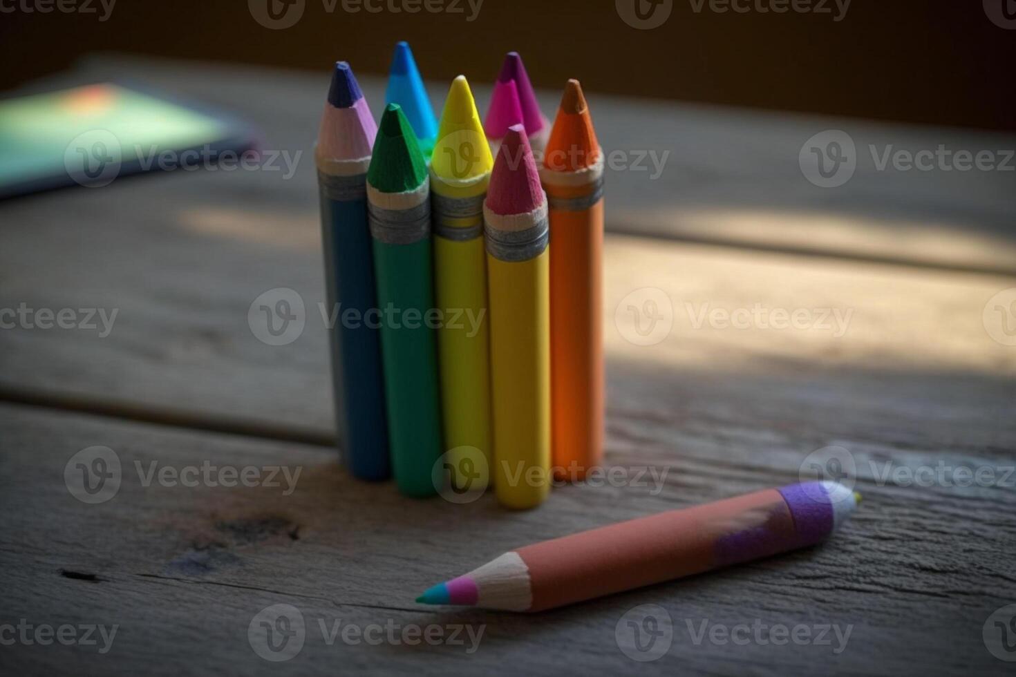 A close-up shot of colourful crayons on a wooden table with paper photo