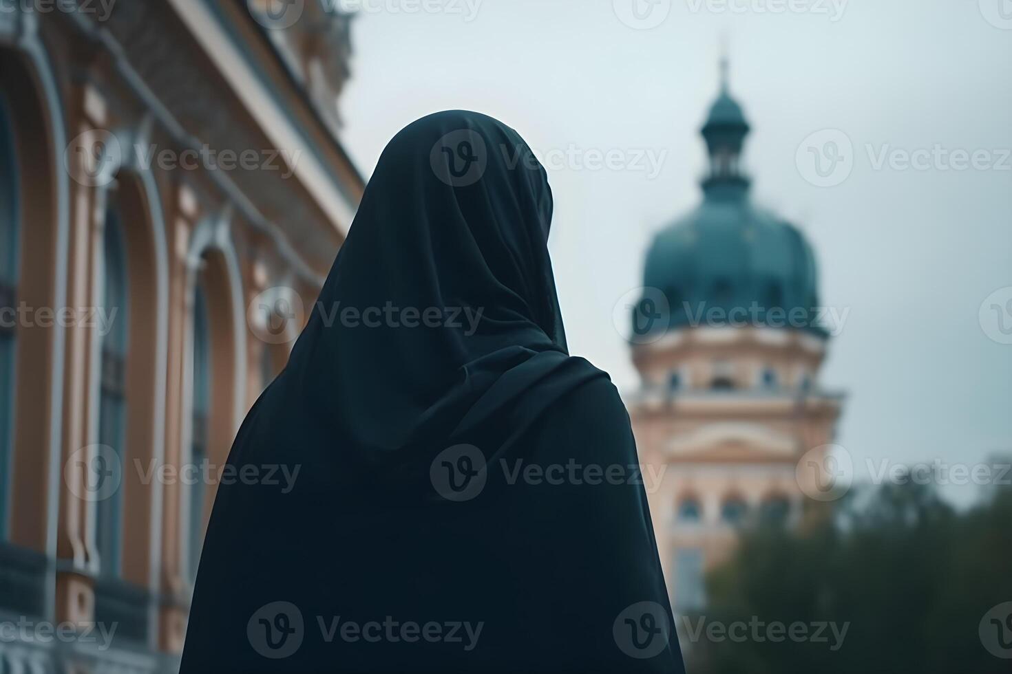 A Muslim woman in a black niqab outfit stands in a courtyard. photo