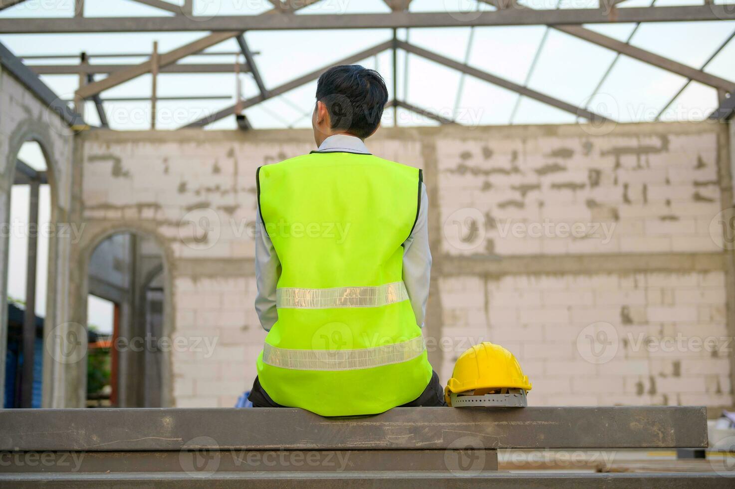 Engineering man with safety helmet siting over construction site background analyzing about project progress photo