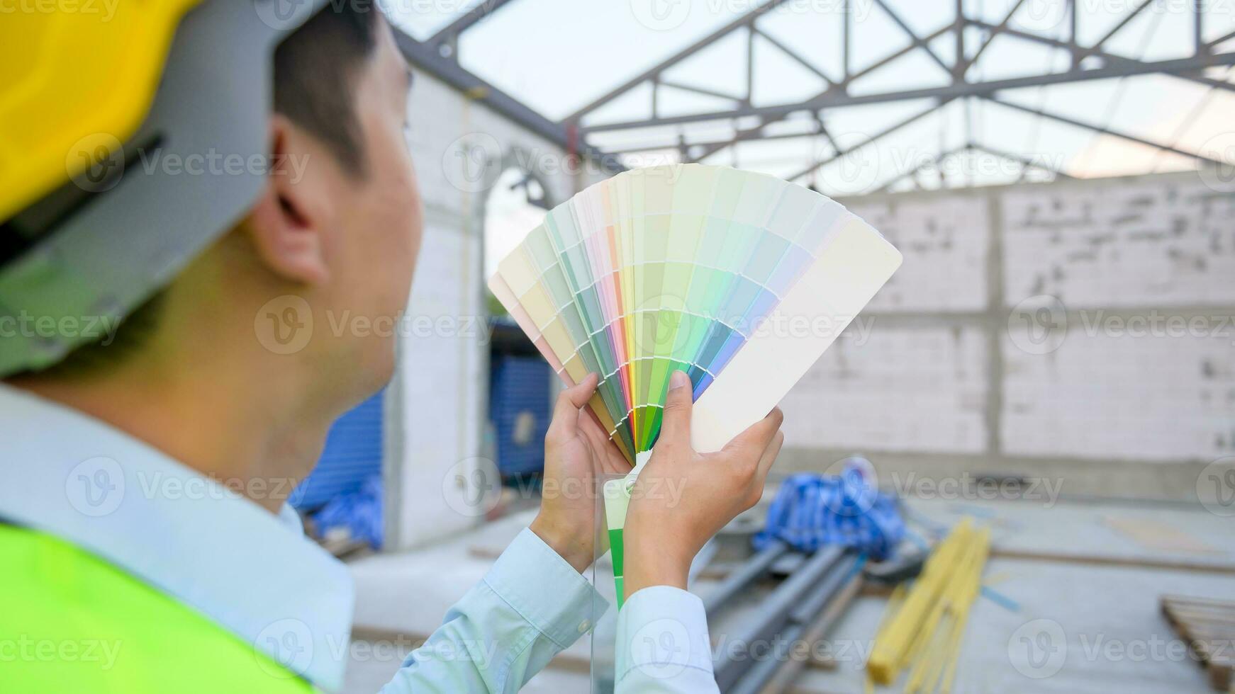 un asiático Ingenieria hombre vistiendo la seguridad casco seleccionando color en construcción sitio foto