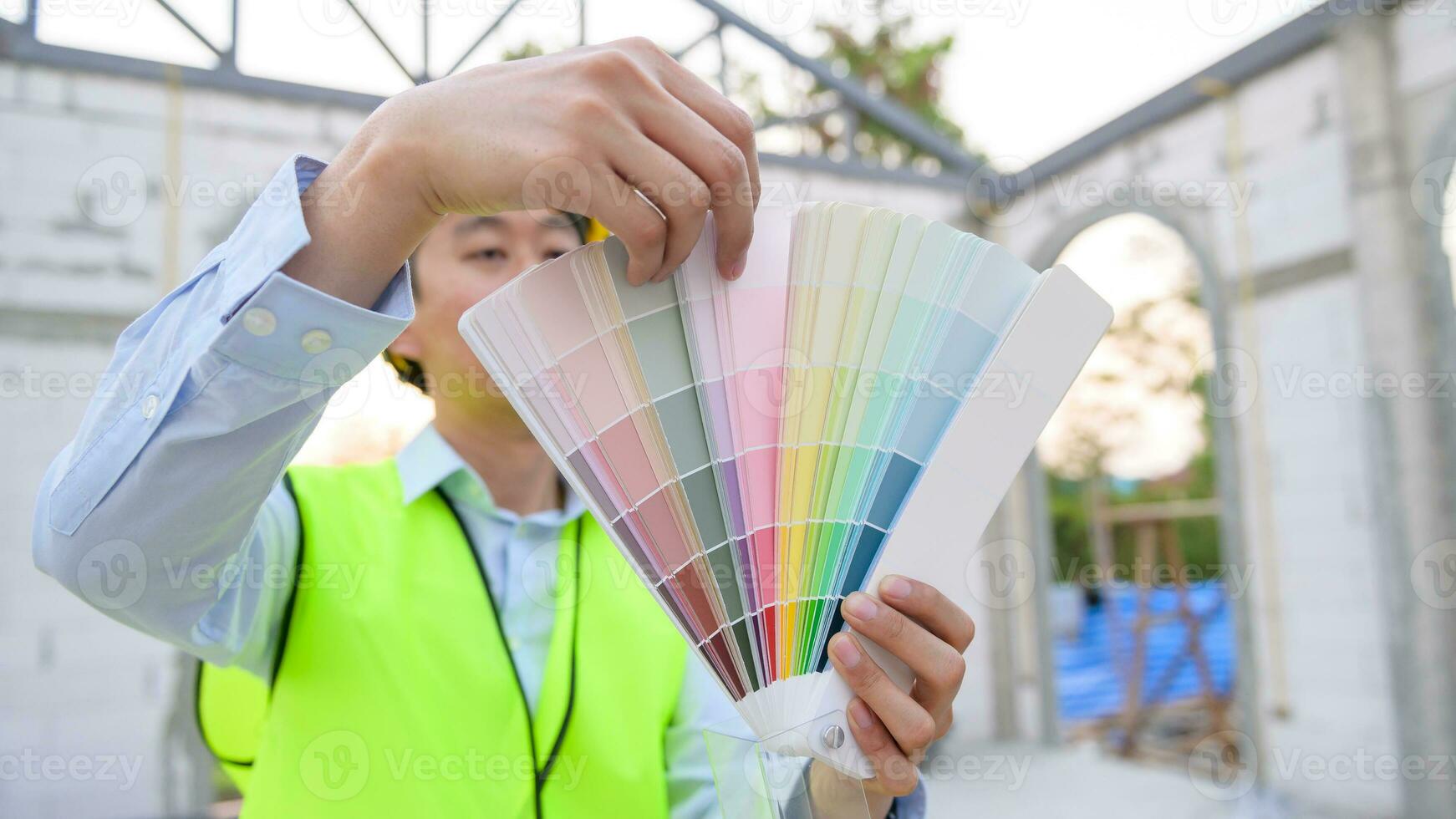 un asiático Ingenieria hombre vistiendo la seguridad casco seleccionando color en construcción sitio foto