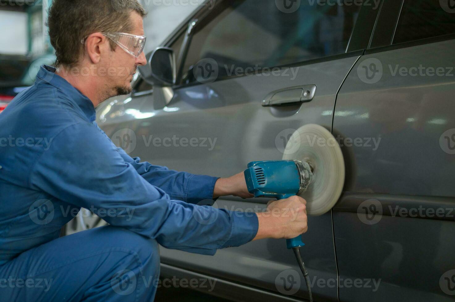 Caucasian man is using car polishing machine in repair mechanic painting shop photo