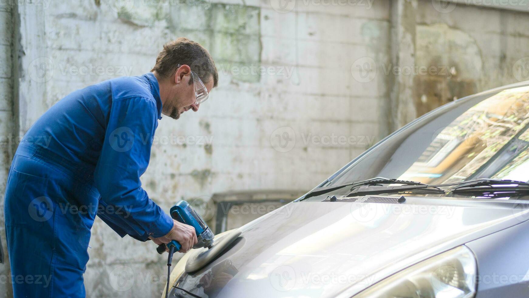 Caucasian man is using car polishing machine in repair mechanic painting shop photo