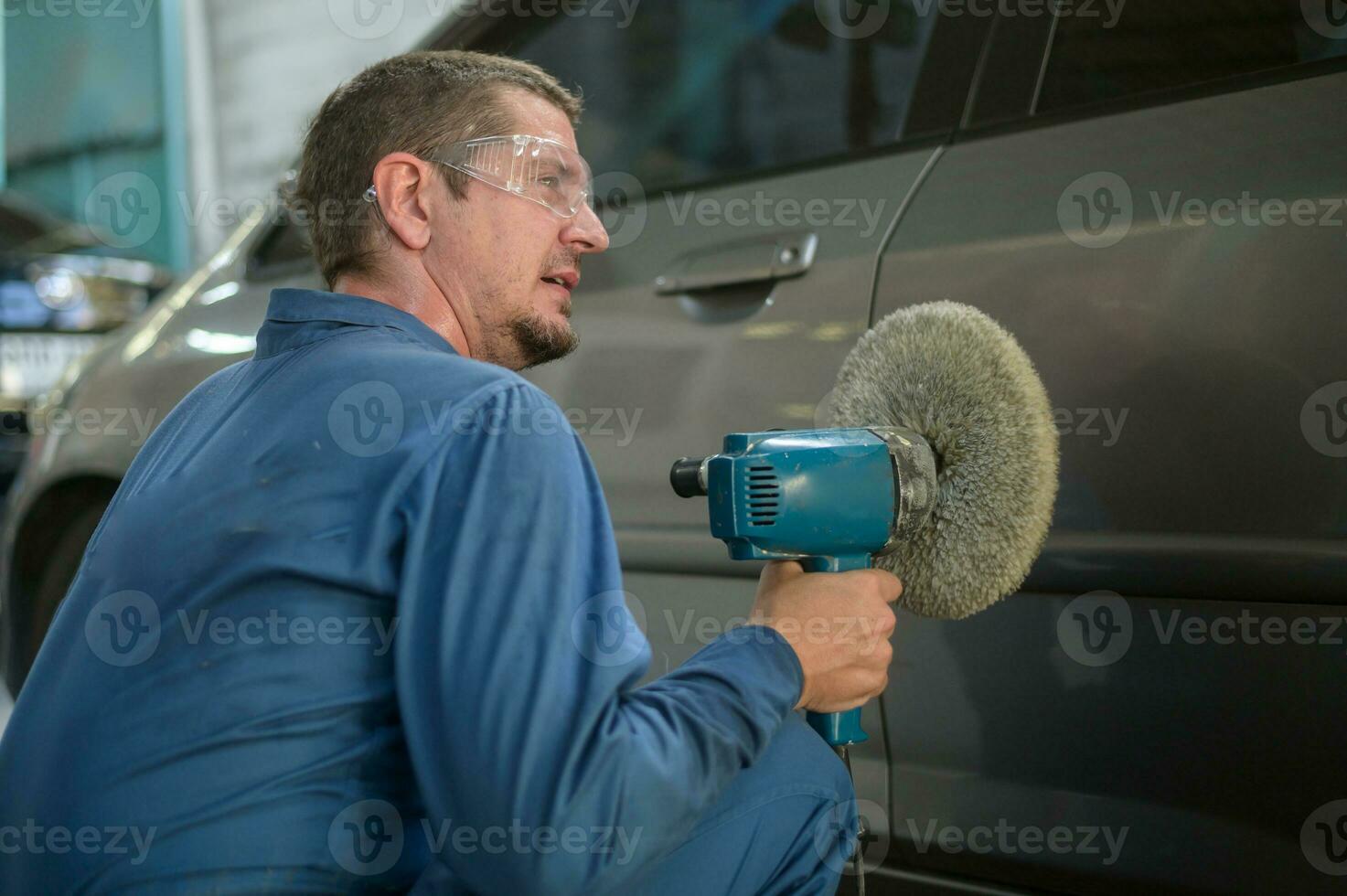 Caucasian man is using car polishing machine in repair mechanic painting shop photo