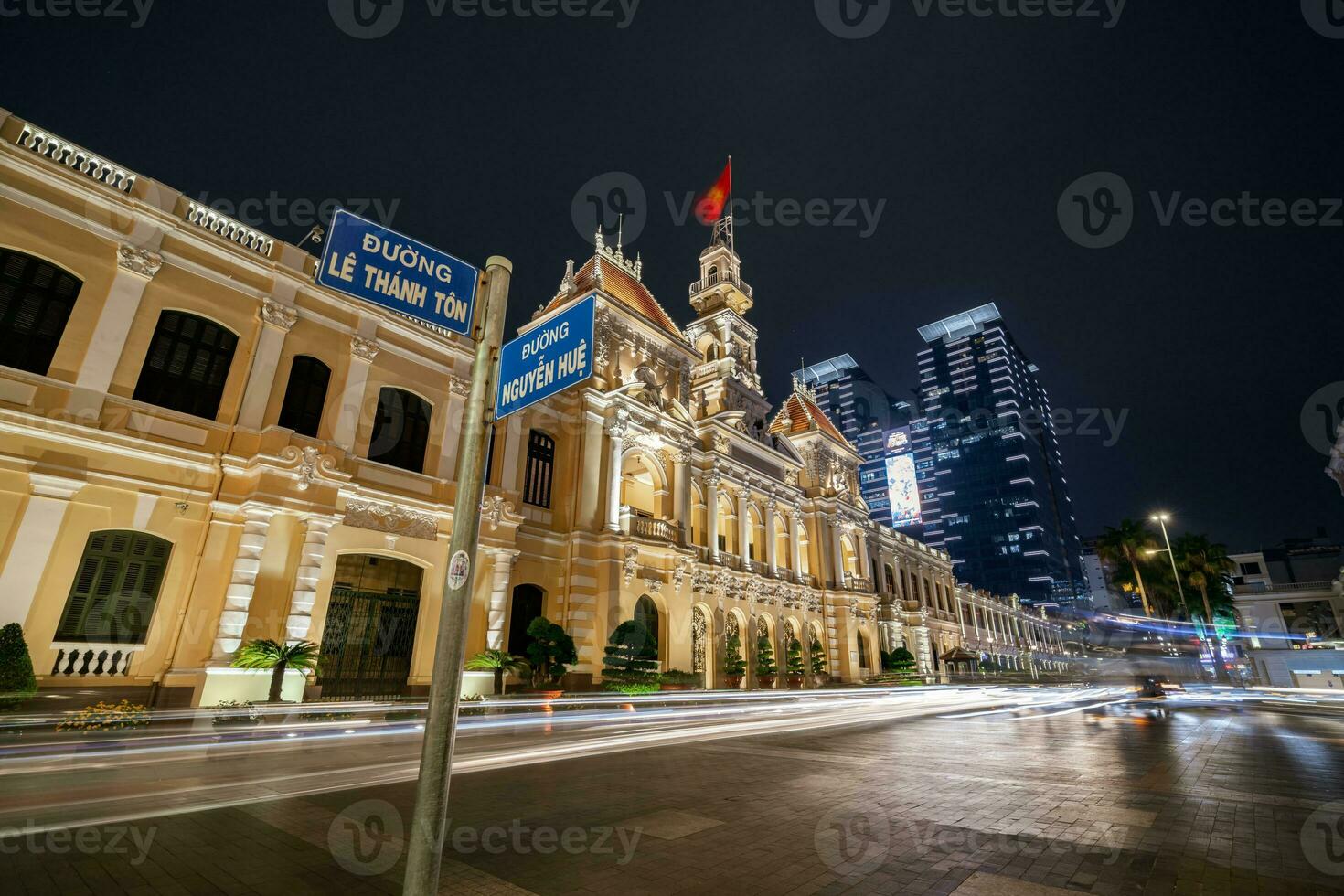 Ho Chi Minh, Viet Nam - 10 April 2023 Saigon City Hall, Vincom Center towers, colorful street traffic and tropical plants against the amazing night. Saigon downtown with its famous landmarks. photo
