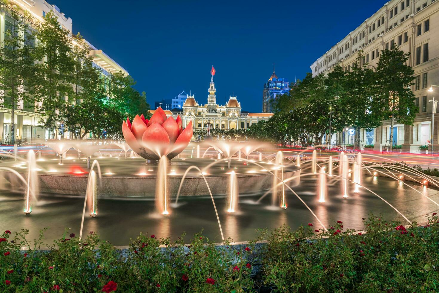 Ho Chi Minh, Viet Nam - 10 April 2023 Saigon City Hall, Vincom Center towers, colorful street traffic and tropical plants against the amazing night. Saigon downtown with its famous landmarks. photo