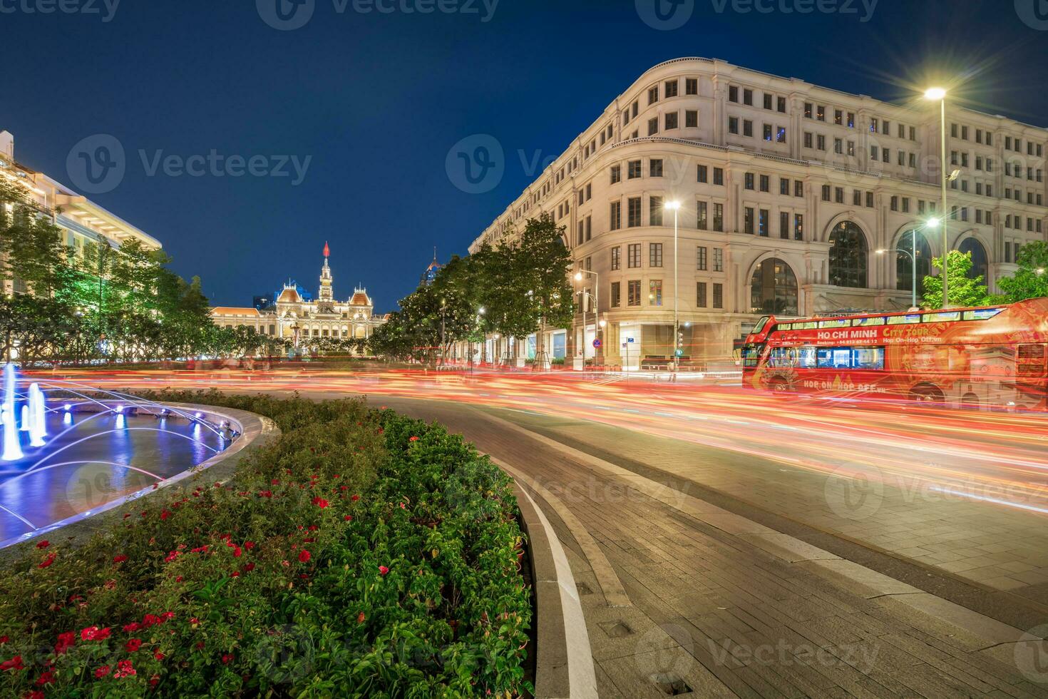 Ho Chi Minh, Viet Nam - 10 April 2023 Saigon City Hall, Vincom Center towers, colorful street traffic and tropical plants against the amazing night. Saigon downtown with its famous landmarks. photo