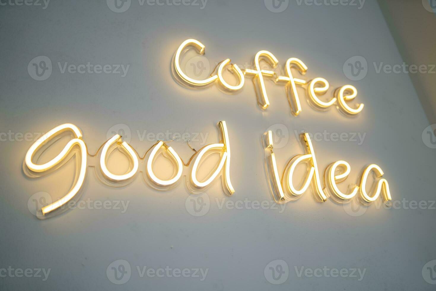 A yellow neon sign on white wall at coffee shop. photo