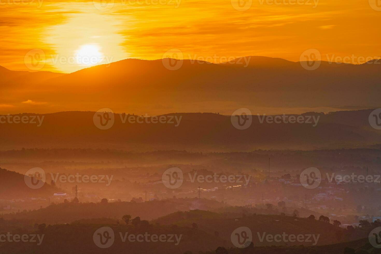 Mountain range with visible silhouettes through the morning colorful fog photo