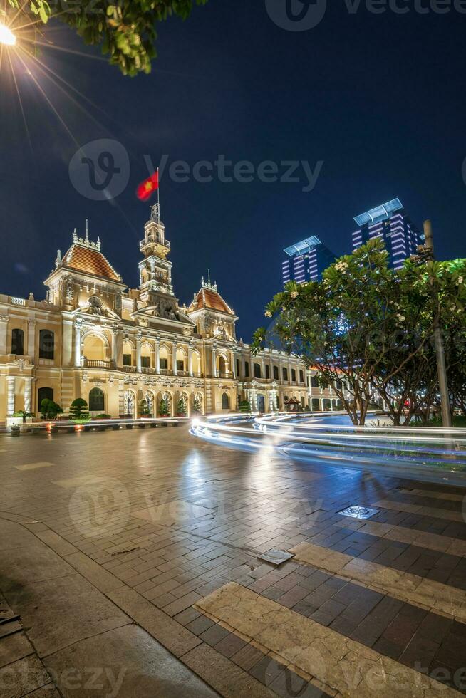 Ho Chi Minh, Viet Nam - 10 April 2023 Saigon City Hall, Vincom Center towers, colorful street traffic and tropical plants against the amazing night. Saigon downtown with its famous landmarks. photo