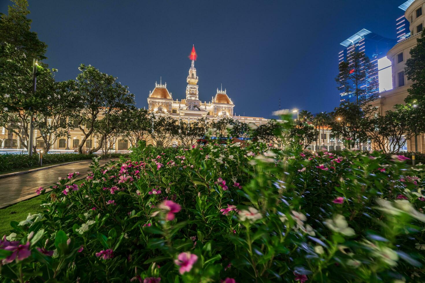 Ho Chi Minh, Viet Nam - 10 April 2023 Saigon City Hall, Vincom Center towers, colorful street traffic and tropical plants against the amazing night. Saigon downtown with its famous landmarks. photo