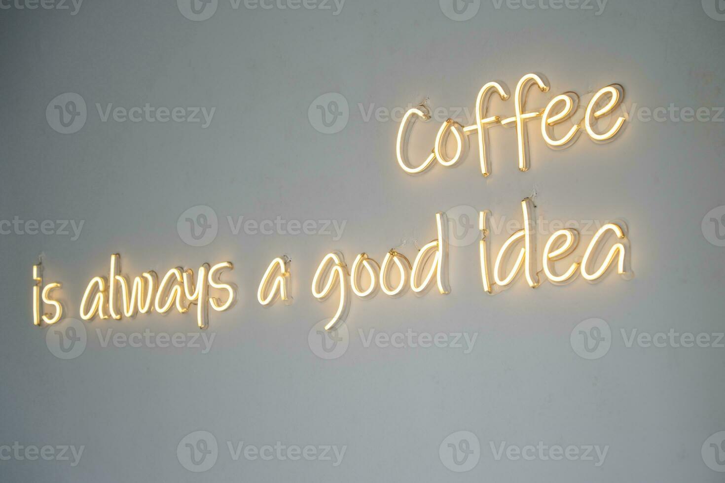 A yellow neon sign on white wall at coffee shop. photo