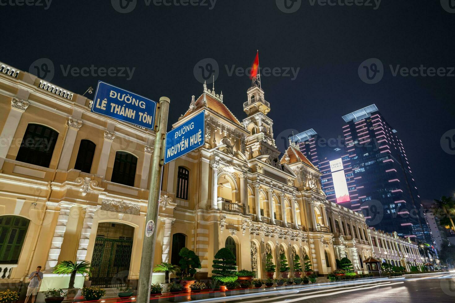 Ho Chi Minh, Viet Nam - 10 April 2023 Saigon City Hall, Vincom Center towers, colorful street traffic and tropical plants against the amazing night. Saigon downtown with its famous landmarks. photo