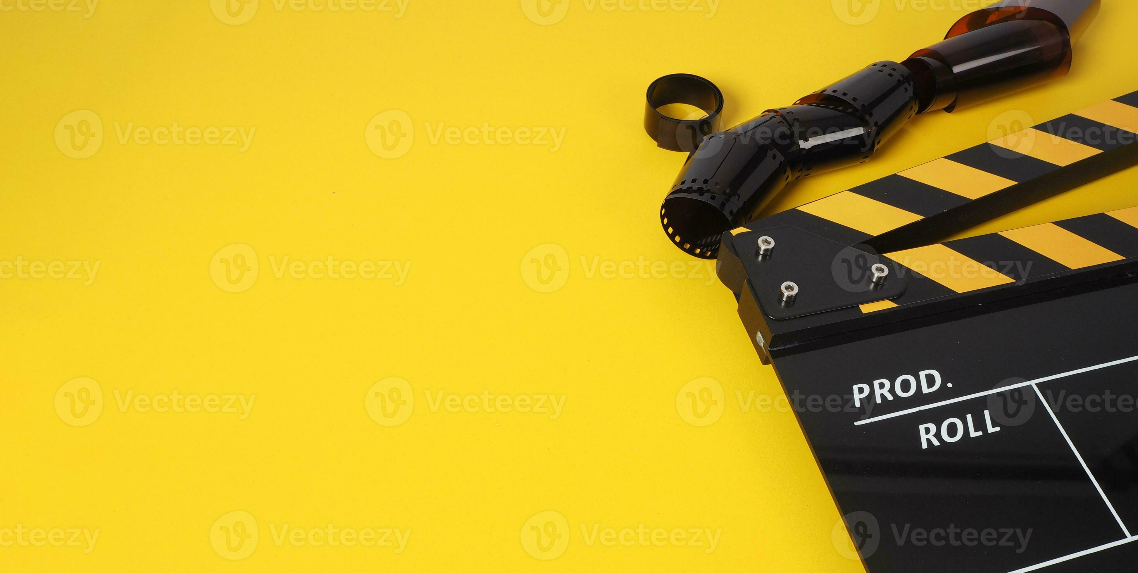 Clapper board in yellow and black color and film roll on yellow