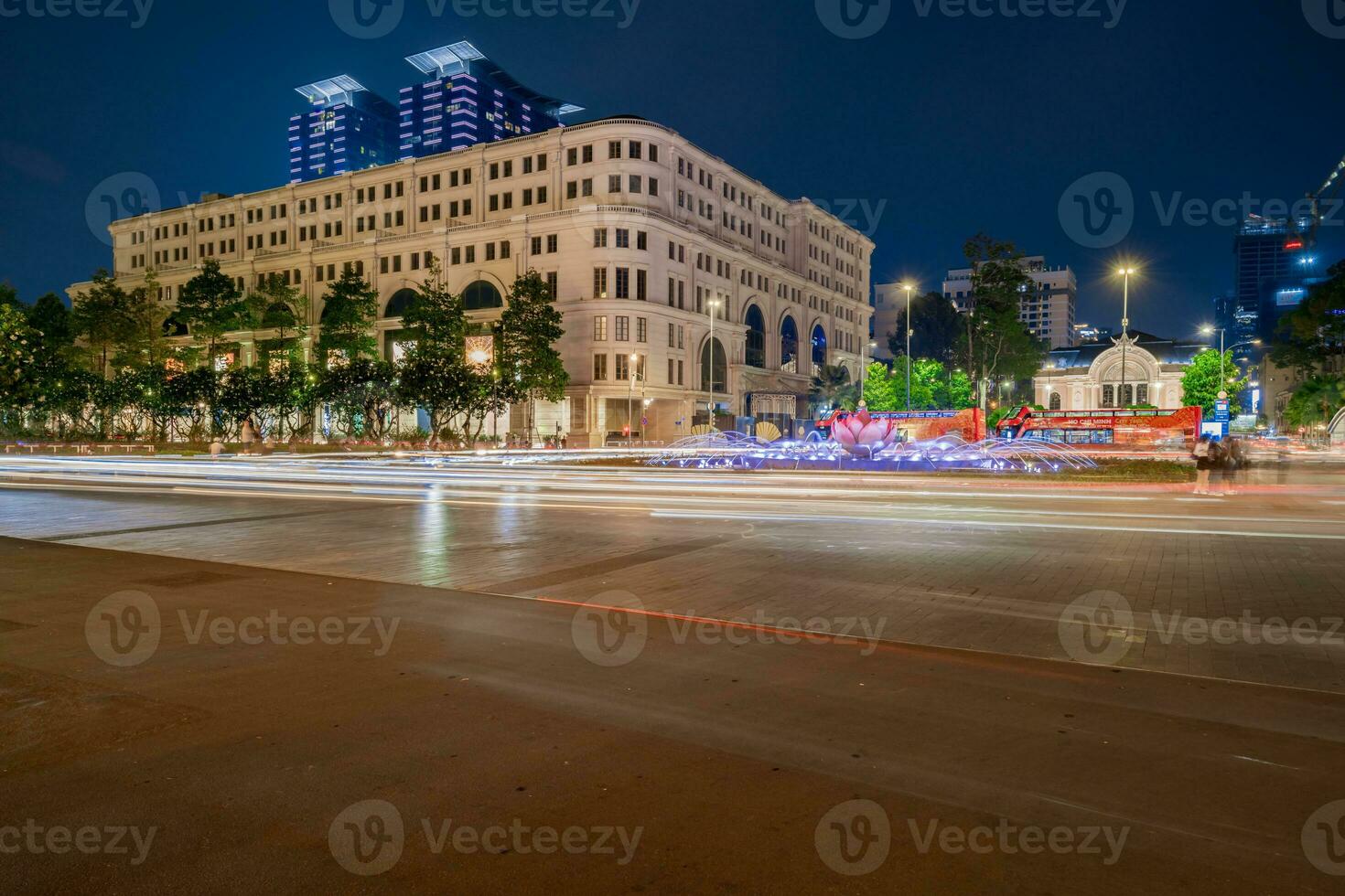 Ho Chi Minh, Viet Nam - 10 April 2023 Saigon City Hall, Vincom Center towers, colorful street traffic and tropical plants against the amazing night. Saigon downtown with its famous landmarks. photo