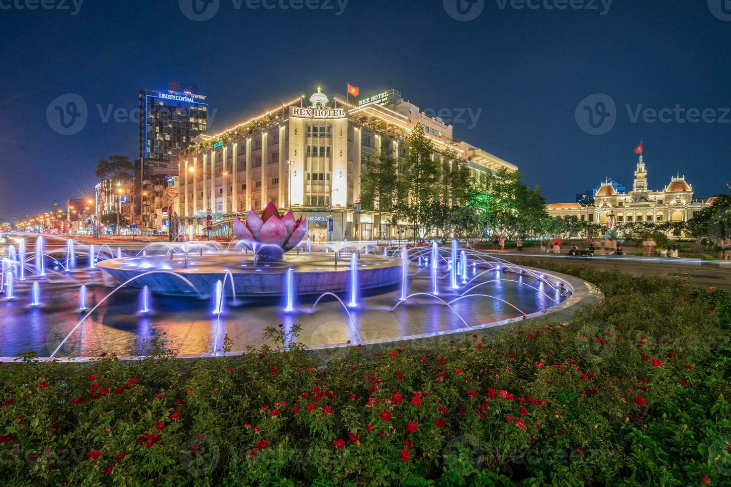 Ho Chi Minh, Viet Nam - 10 April 2023 Saigon City Hall, Vincom Center towers, colorful street traffic and tropical plants against the amazing night. Saigon downtown with its famous landmarks. photo