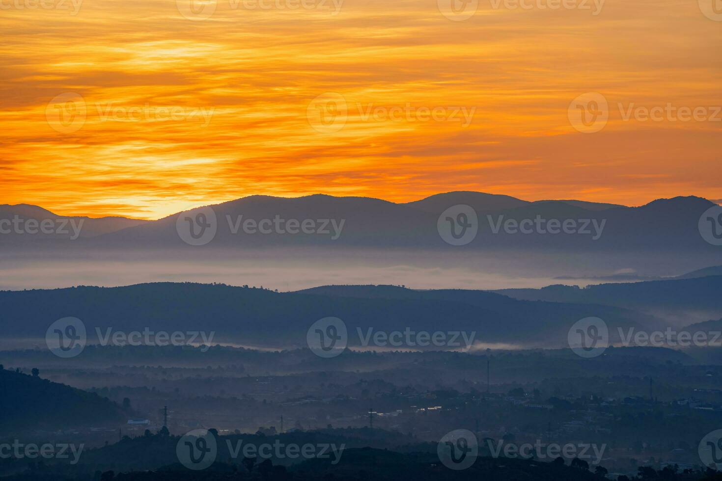 Mountain range with visible silhouettes through the morning colorful fog photo