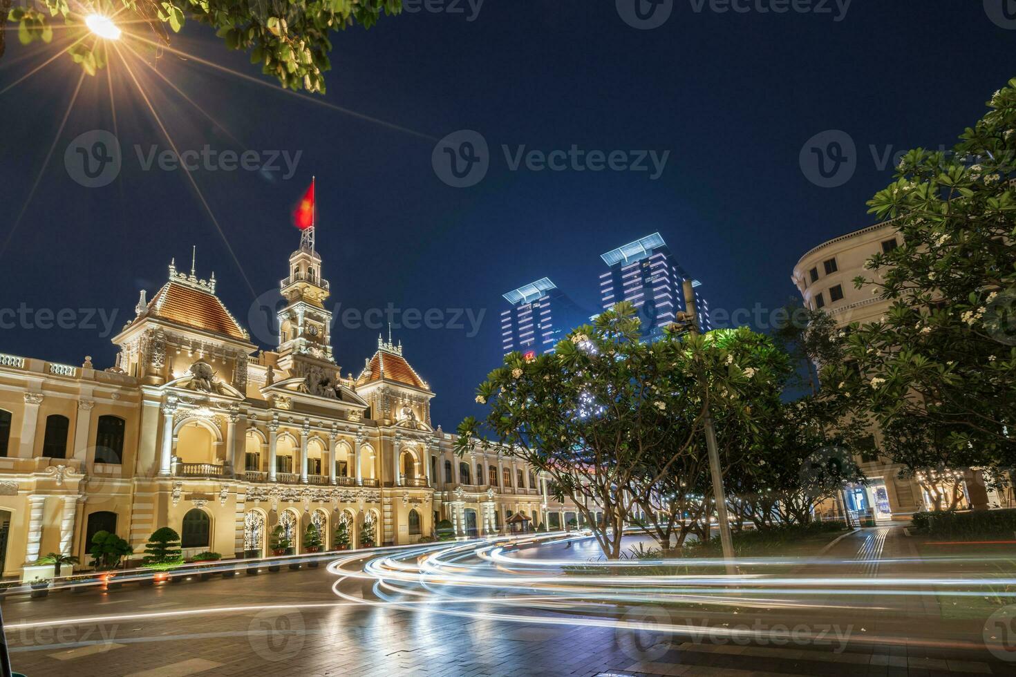 Ho Chi Minh, Viet Nam - 10 April 2023 Saigon City Hall, Vincom Center towers, colorful street traffic and tropical plants against the amazing night. Saigon downtown with its famous landmarks. photo