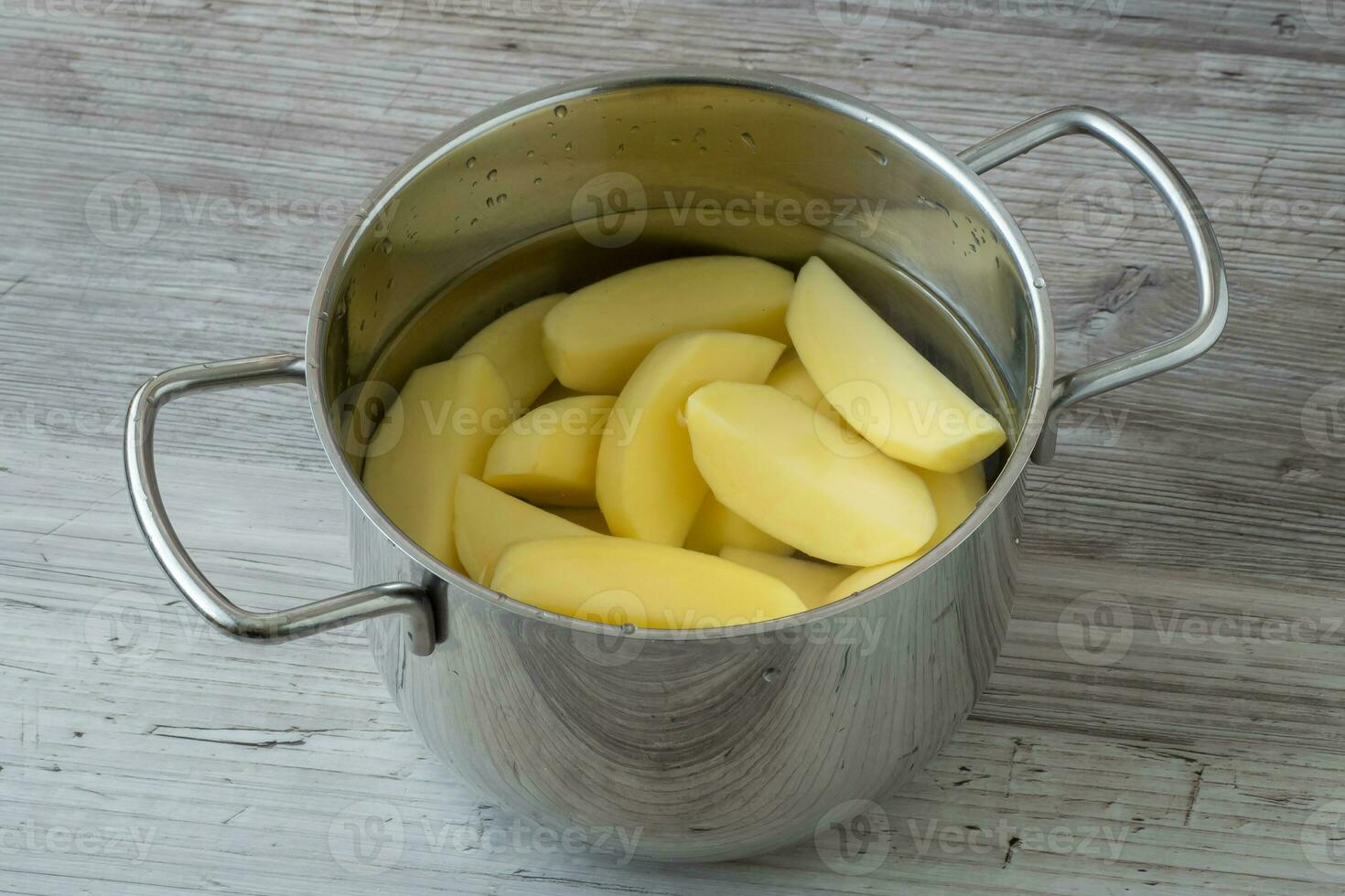 patatas peladas crudas en una olla de agua antes de cocinar foto