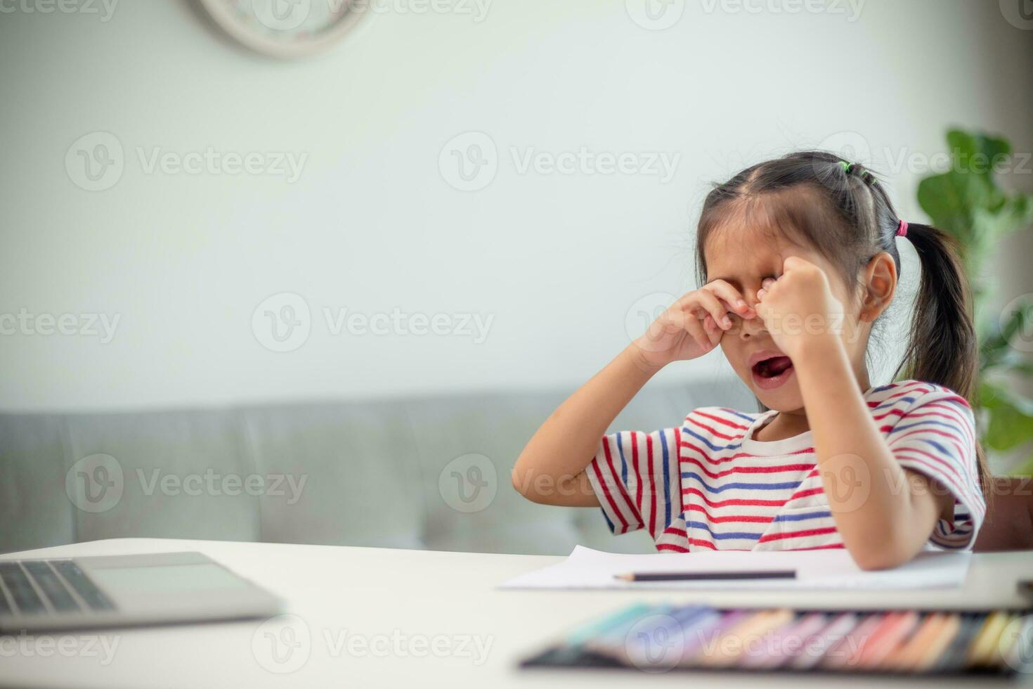 Asian child is yawning and bored while studying online at home. photo
