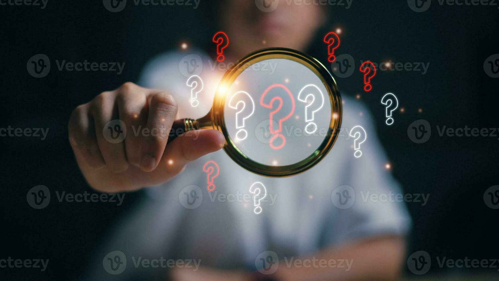 The concept of finding an answer to complex questions in business. Hand holding a magnifying glass with a question mark. photo