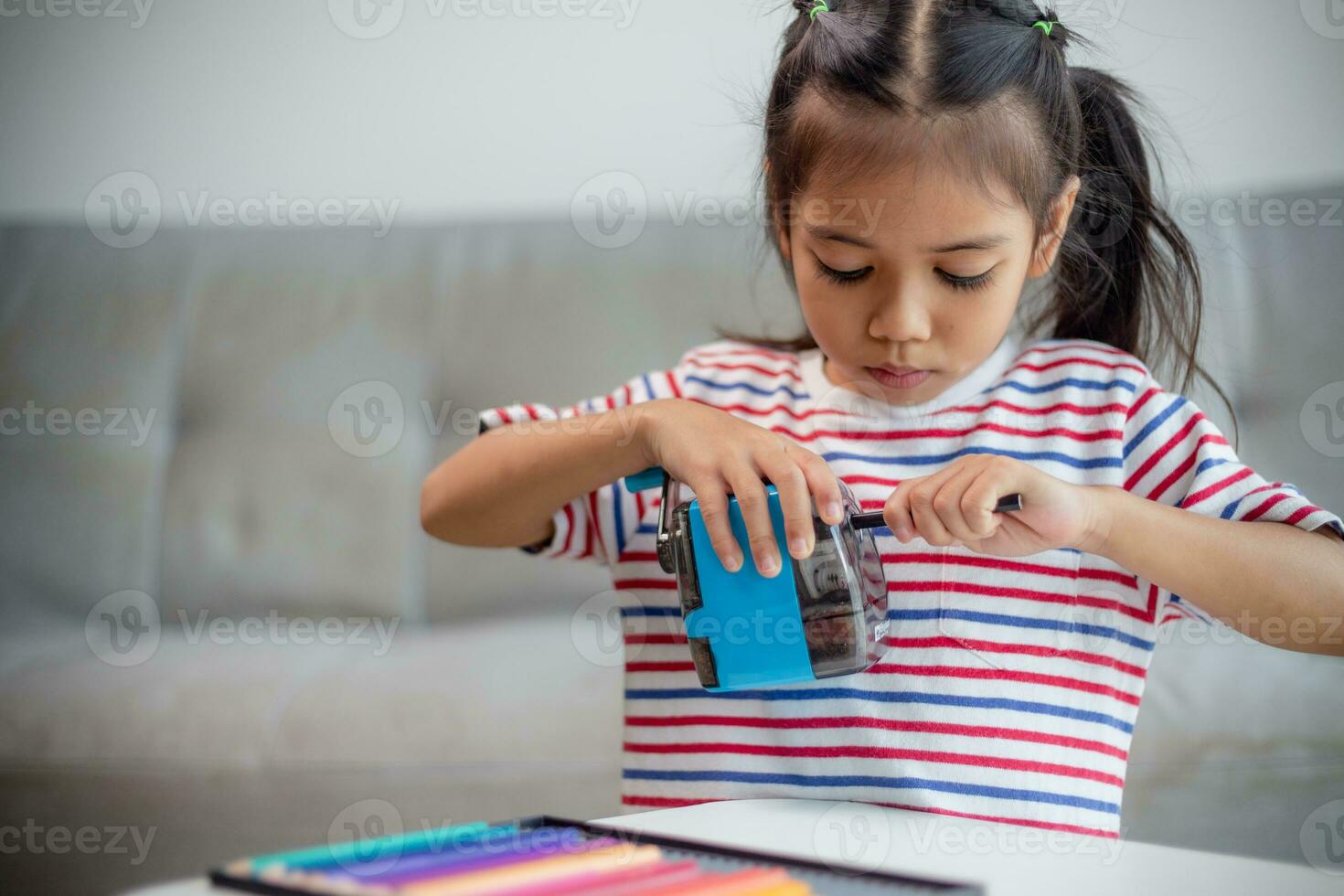 Student child girl using Pencil sharpener while doing homework. education concept. photo