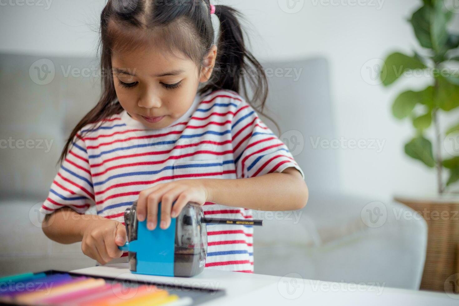 Student child girl using Pencil sharpener while doing homework. education concept. photo