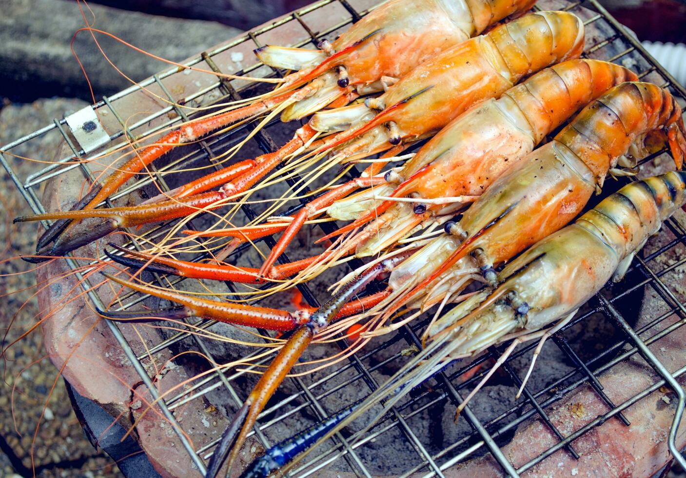 Home cooks are grilling prawns on a charcoal stove. photo