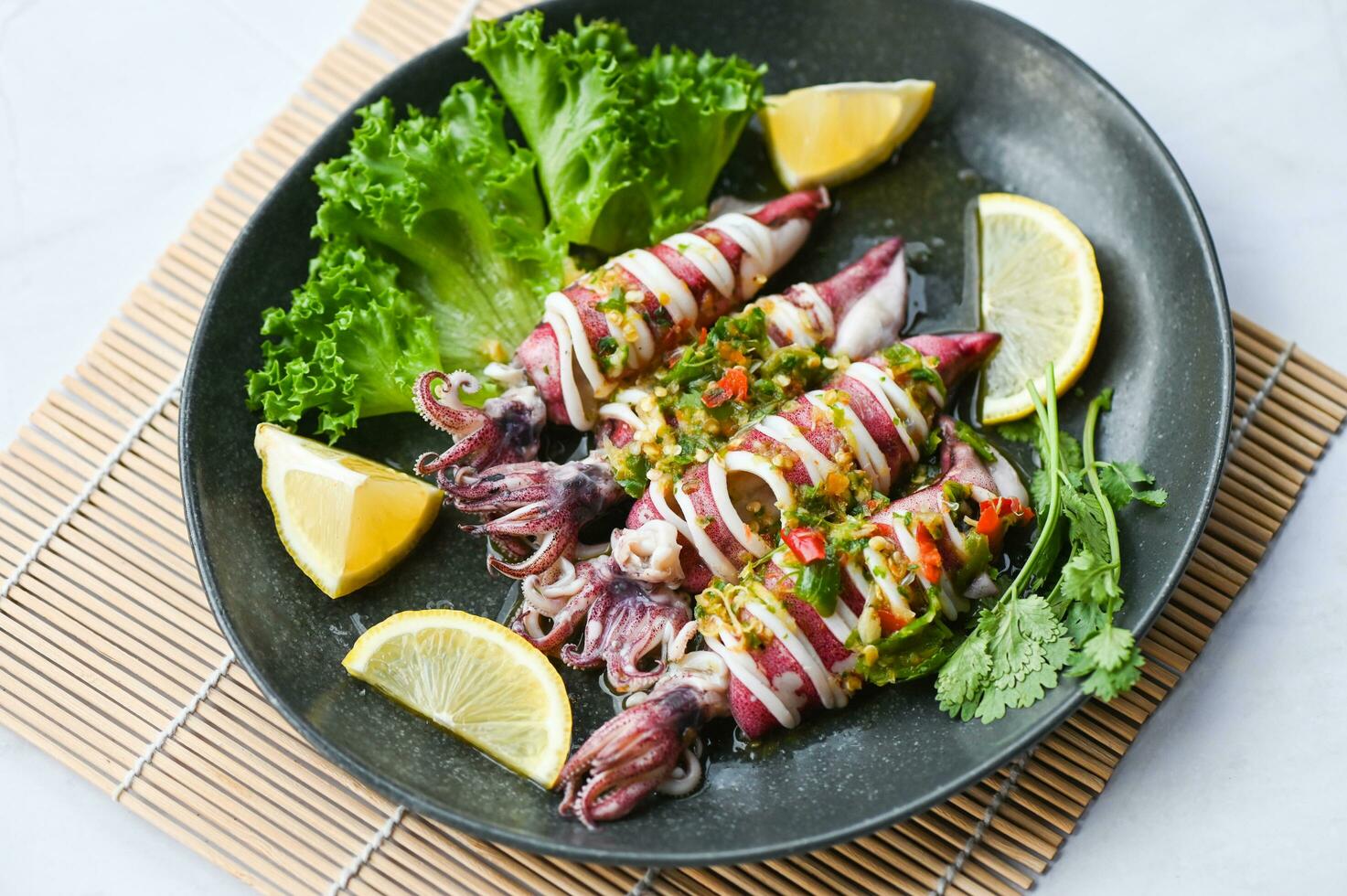 Steamed squid with lemon spicy chili and lemon sauce squid steamed with lime, Thai food seafood plate with herb and spices - top view photo