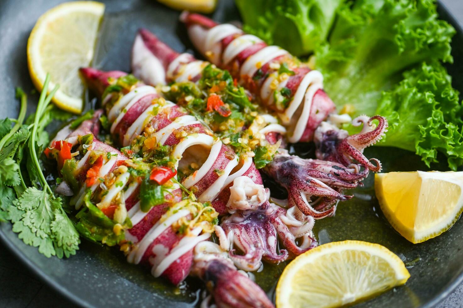 Thai food seafood plate with herb and spices, Steamed squid with lemon spicy chili and lemon sauce squid steamed with lime - top view photo