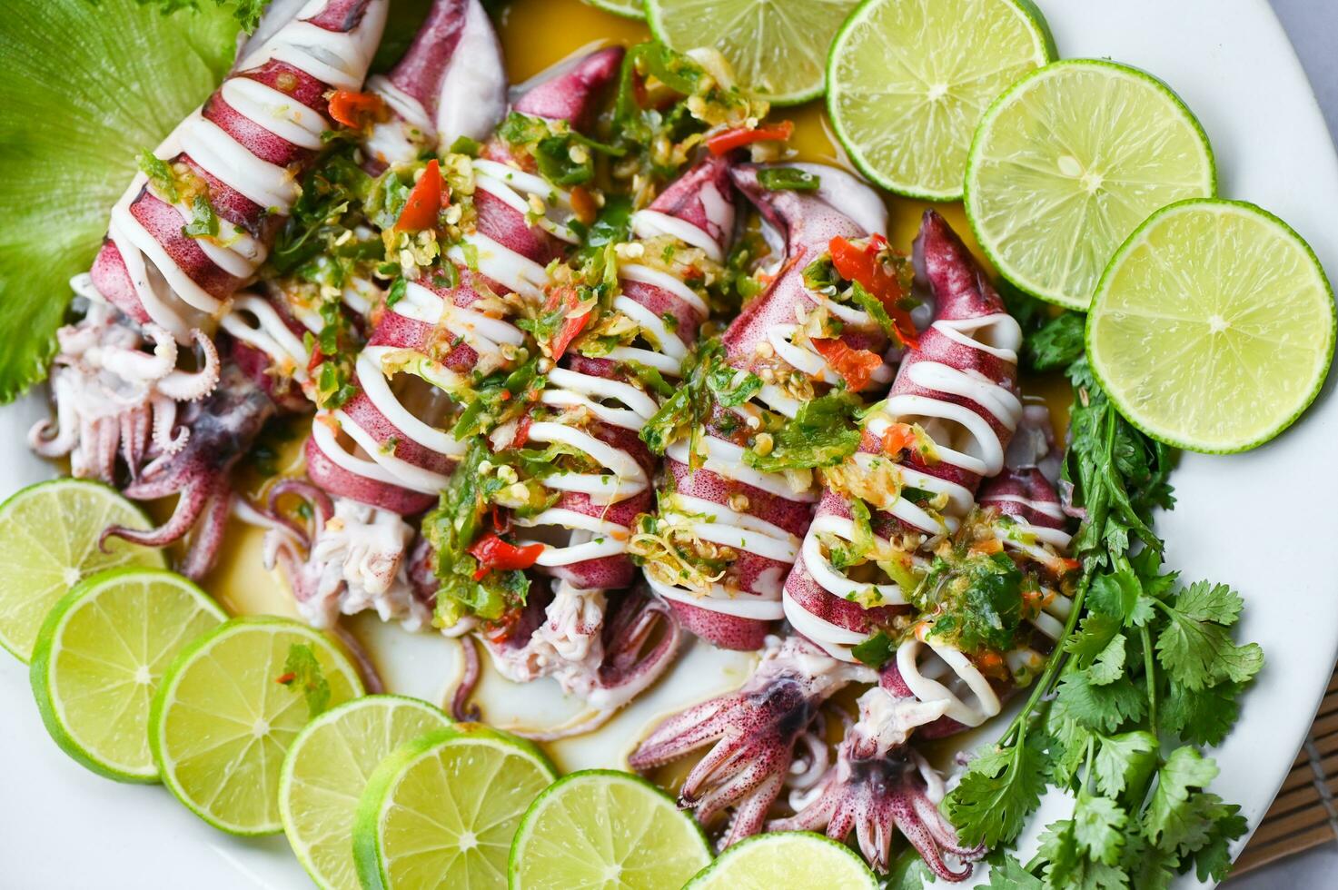 Steamed squid with lemon spicy chili and lemon sauce squid steamed with lime, Thai food seafood plate with herb and spices - top view photo
