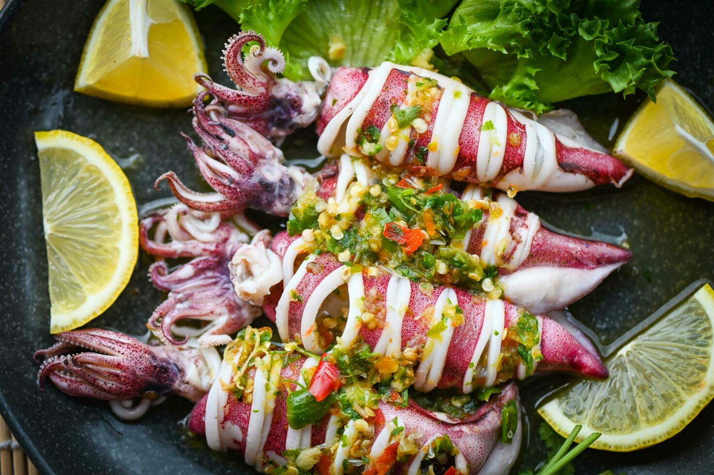 Thai food seafood plate with herb and spices, Steamed squid with lemon spicy chili and lemon sauce squid steamed with lime - top view photo