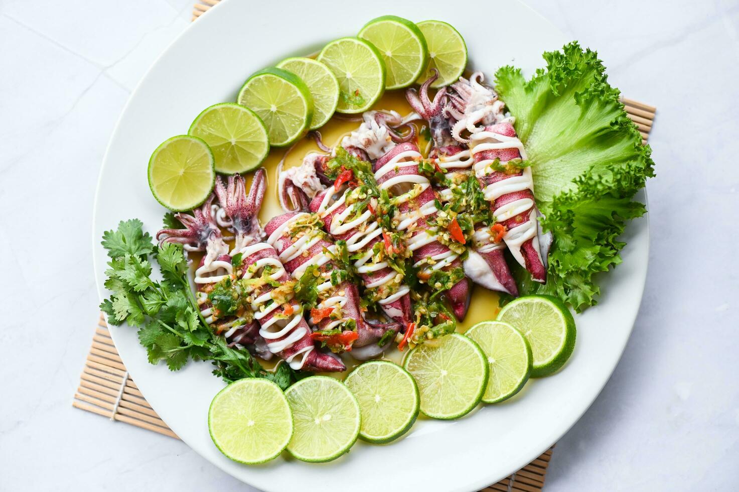 Steamed squid with lemon spicy chili and lemon sauce squid steamed with lime, Thai food seafood plate with herb and spices - top view photo