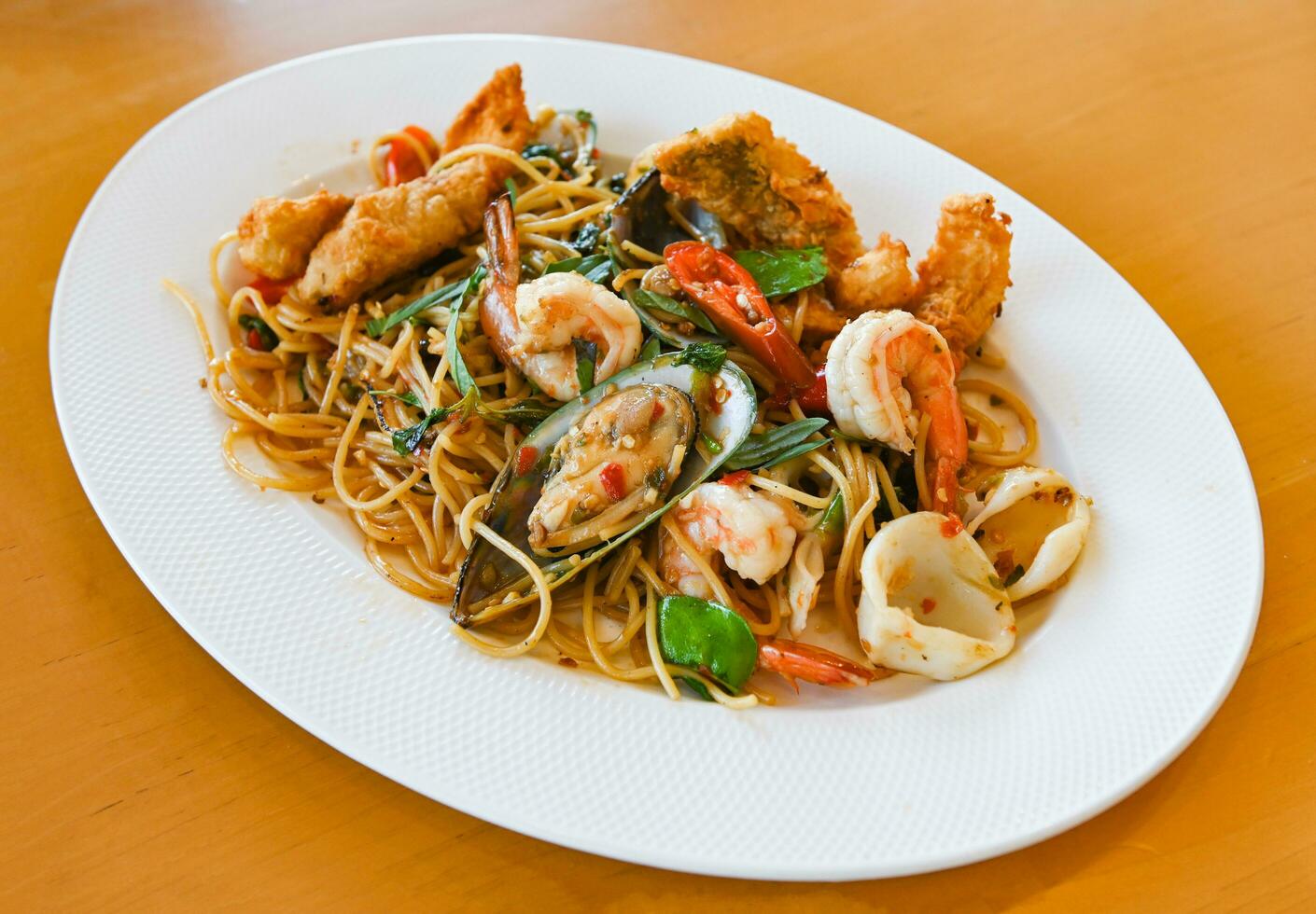 noodles plate with spaghetti pasta stir fried with vegetables herb spicy tasty appetizing asian noodles mix seafood stir fried shrimp squid shellfish fish with basil and chilli pepper photo