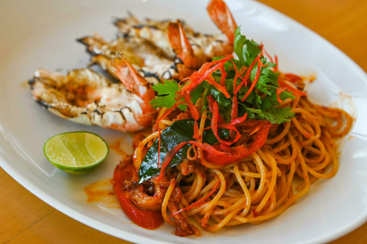 noodles plate with spaghetti pasta stir fried with vegetables herb spicy tasty appetizing asian noodles mix seafood stir fried shrimp squid shellfish fish with basil and chilli pepper photo