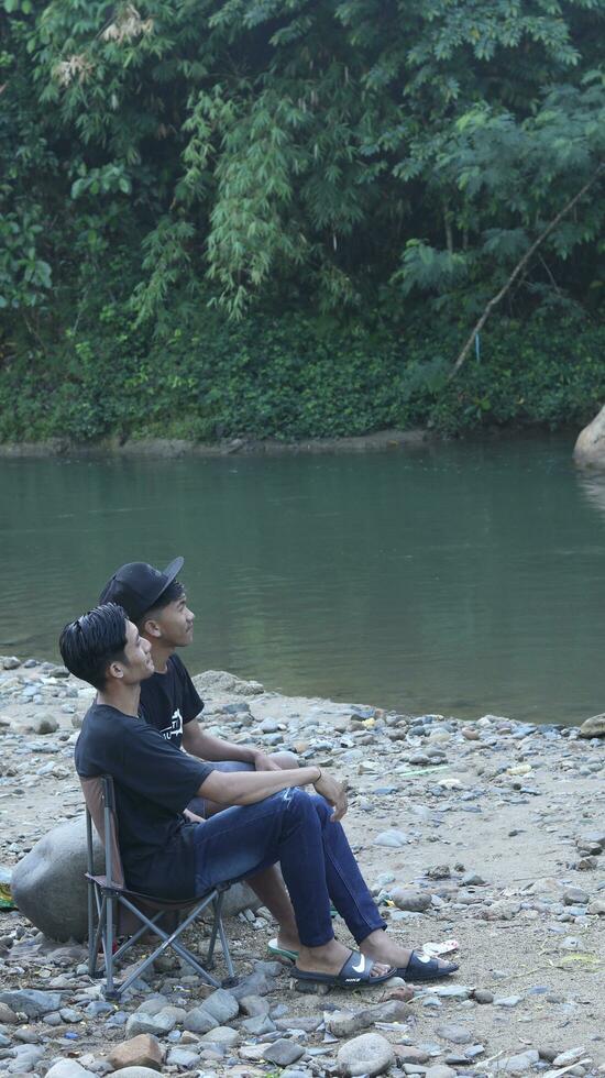 Gorontalo-Indonesia, May 2023 - Young man enjoying the morning atmosphere by the riverside photo