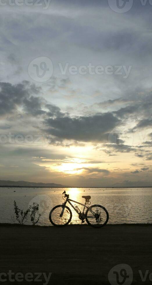 silhouette of a bicycle against the background of the sunset on the lake photo