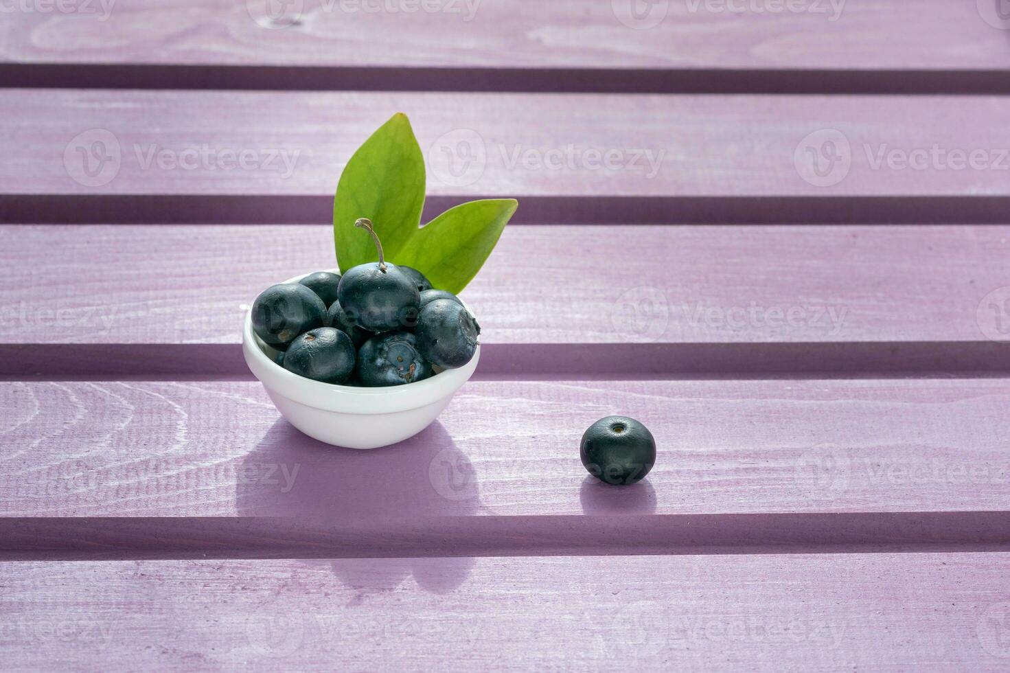 on a purple wooden background is a plate with fresh blueberries photo