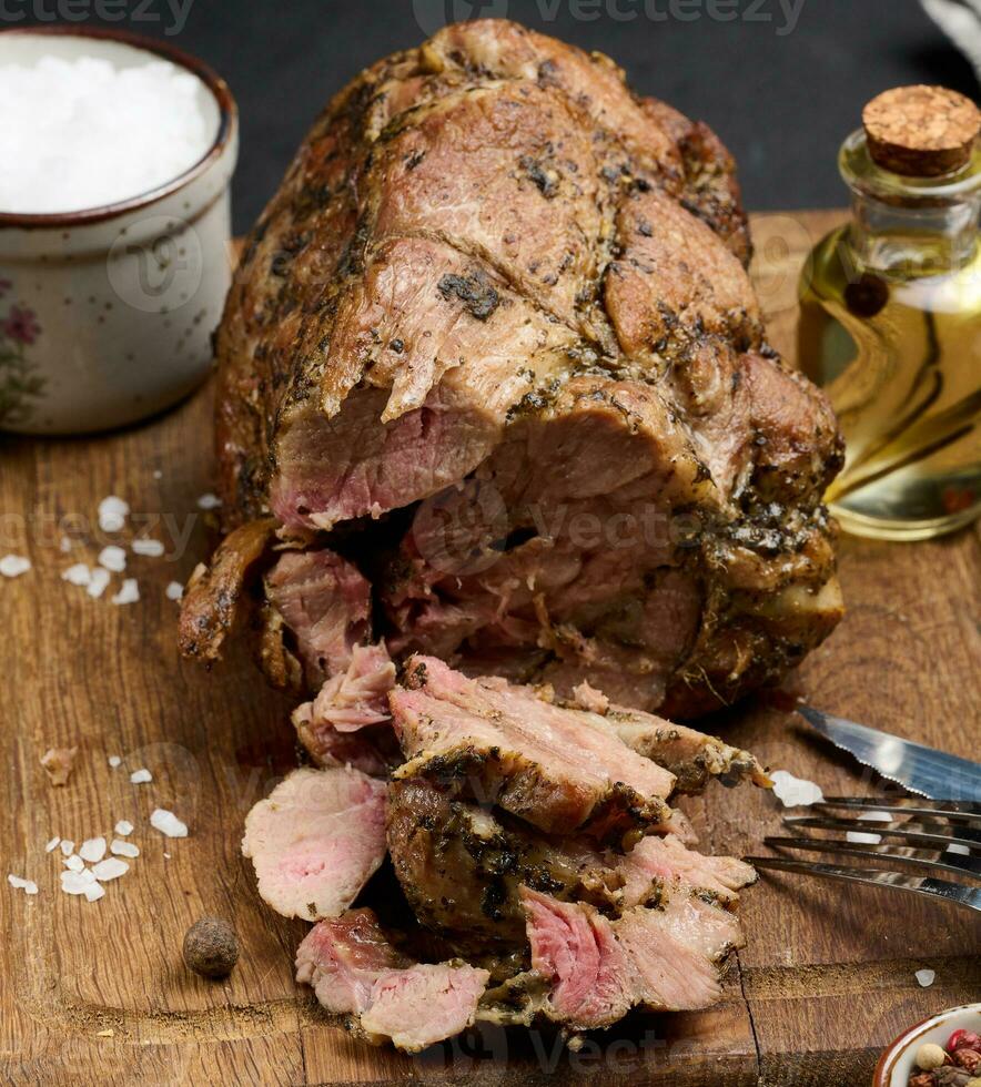 Baked pork collar with spices on a wooden board, delicious and juicy meat photo