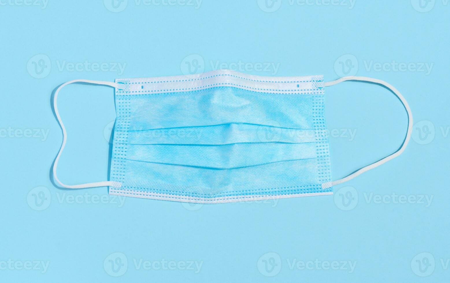 Disposable blue medical face mask against virus protection on a blue background, top view photo