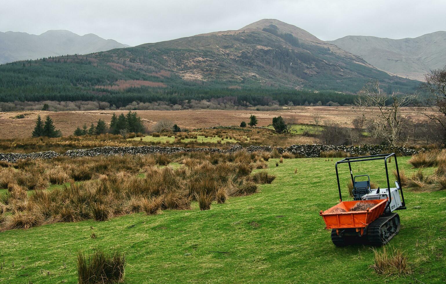 Beautiful rural landscape scenery with machinery on the green meadow surrounded by mountains at Connemara National park, county Galway, Ireland photo